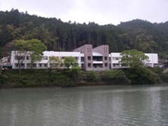 川沿いにあり、白を基調とした建物の日野谷診療所の外観写真