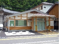道路沿いにあり、平屋作りの建物で、正面玄関横に駐車スペースがある木沢診療所の外観写真