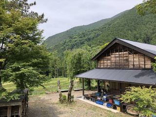 後方には山並みが見える自然豊かな場所に立つゲストハウス杉の子の外観写真