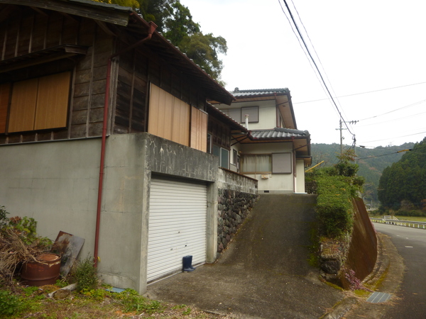 坂道の手前にシャッター付の屋根付き駐車場がある写真