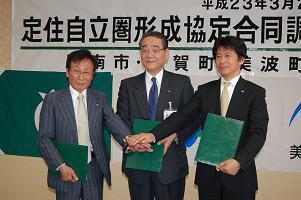 定住自立圏形成協定式の会場にて、阿南市長、那賀町長、美波両町長の3名が手を重ねて記念撮影をしている写真
