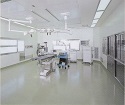 手術台、天井から下げられた照明器具がある手術室の写真