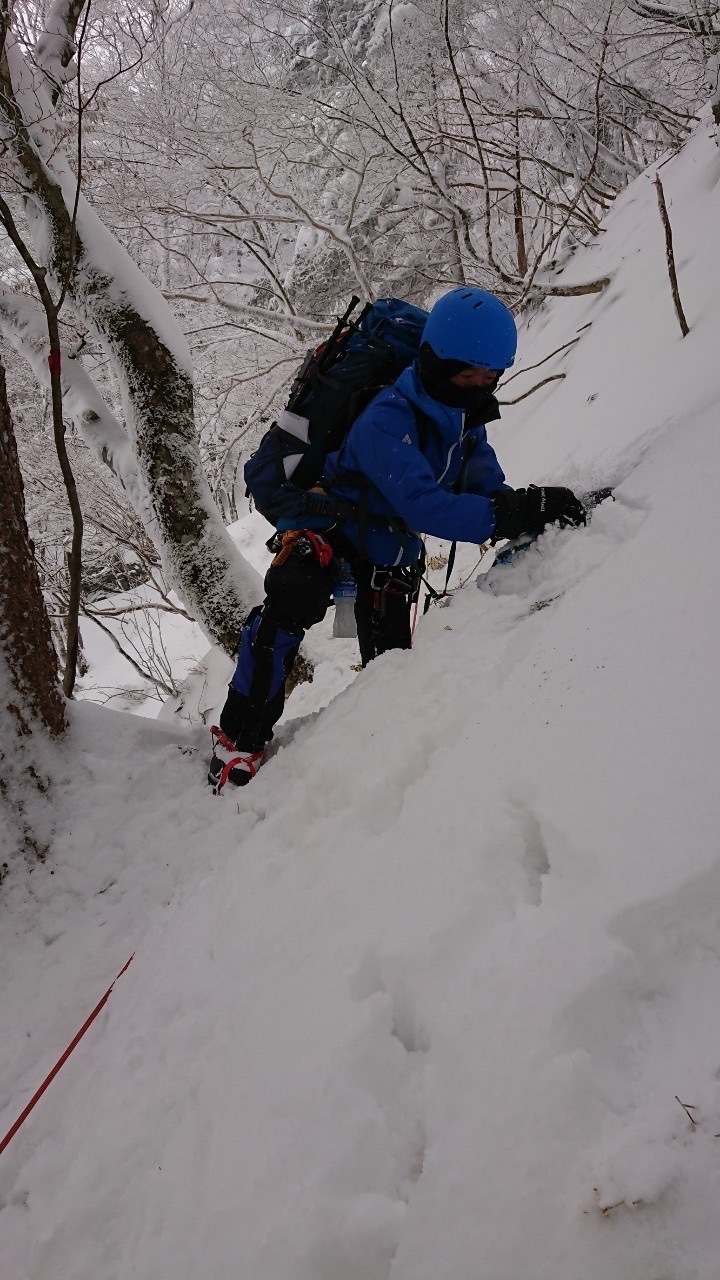 雪の積もった急斜面を、ロープや道具を使いながら登山をしている隊員の写真