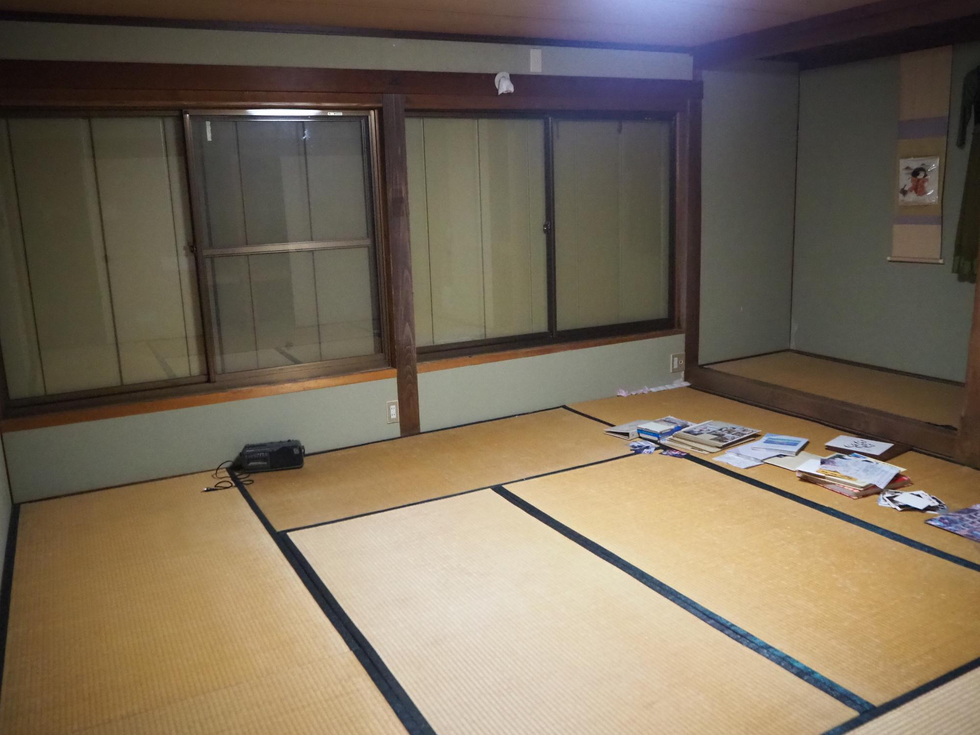 奥に4枚続きの窓は雨戸で閉められた広い和室の写真
