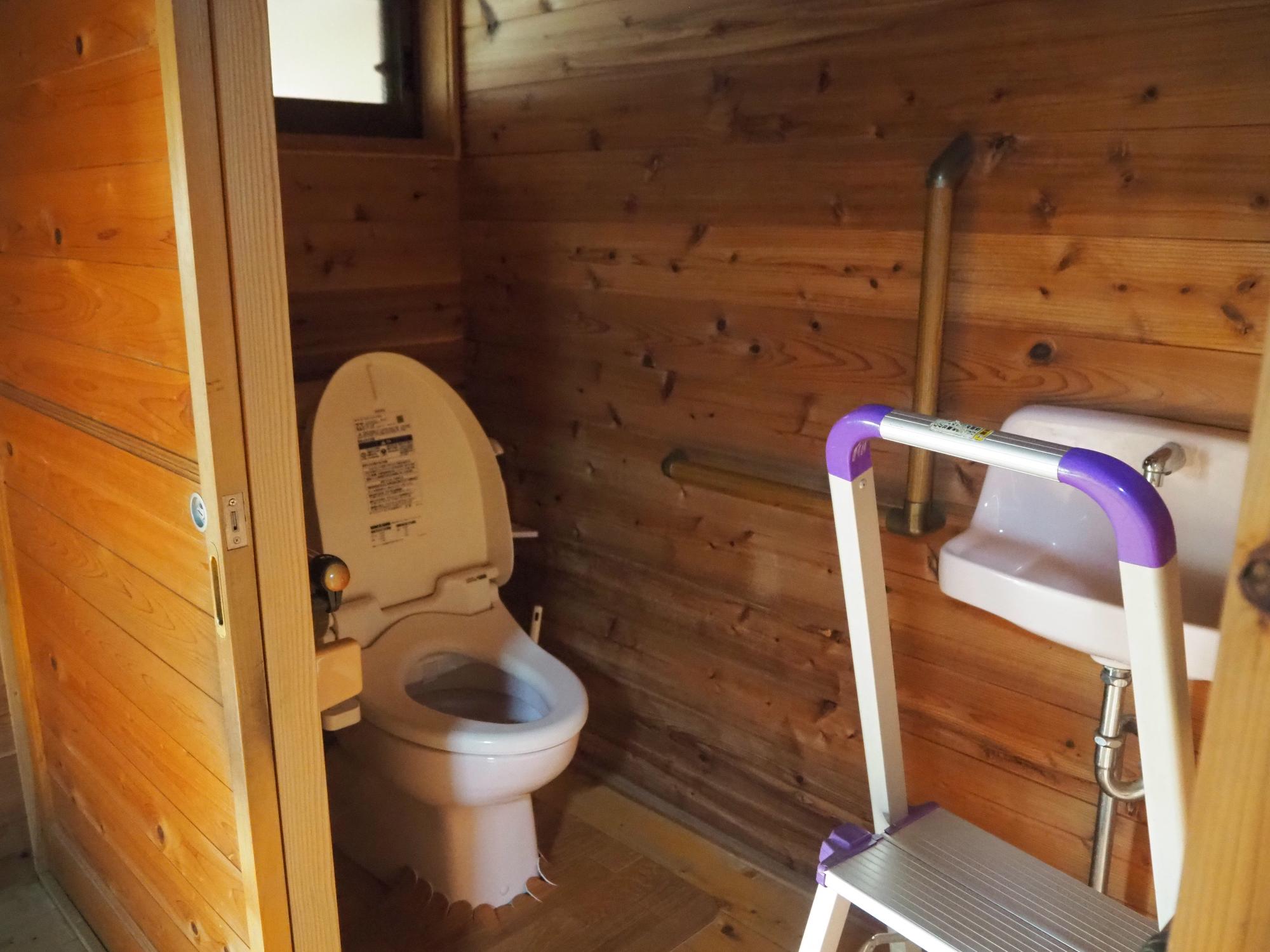 壁・床全面板張りのピンクの便座のトイレの写真