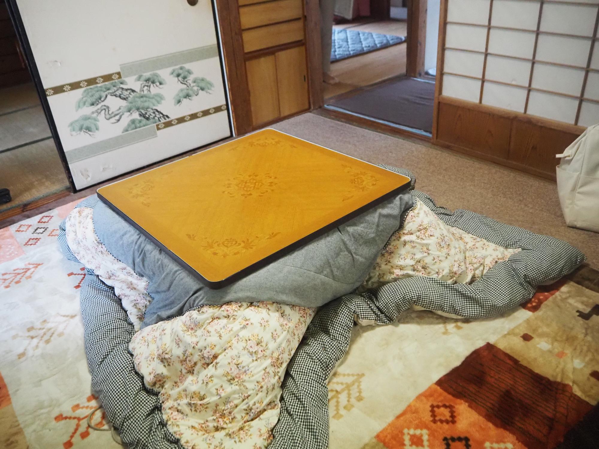 襖と障子で仕切られ部屋の真ん中にこたつが置かれた居間の写真