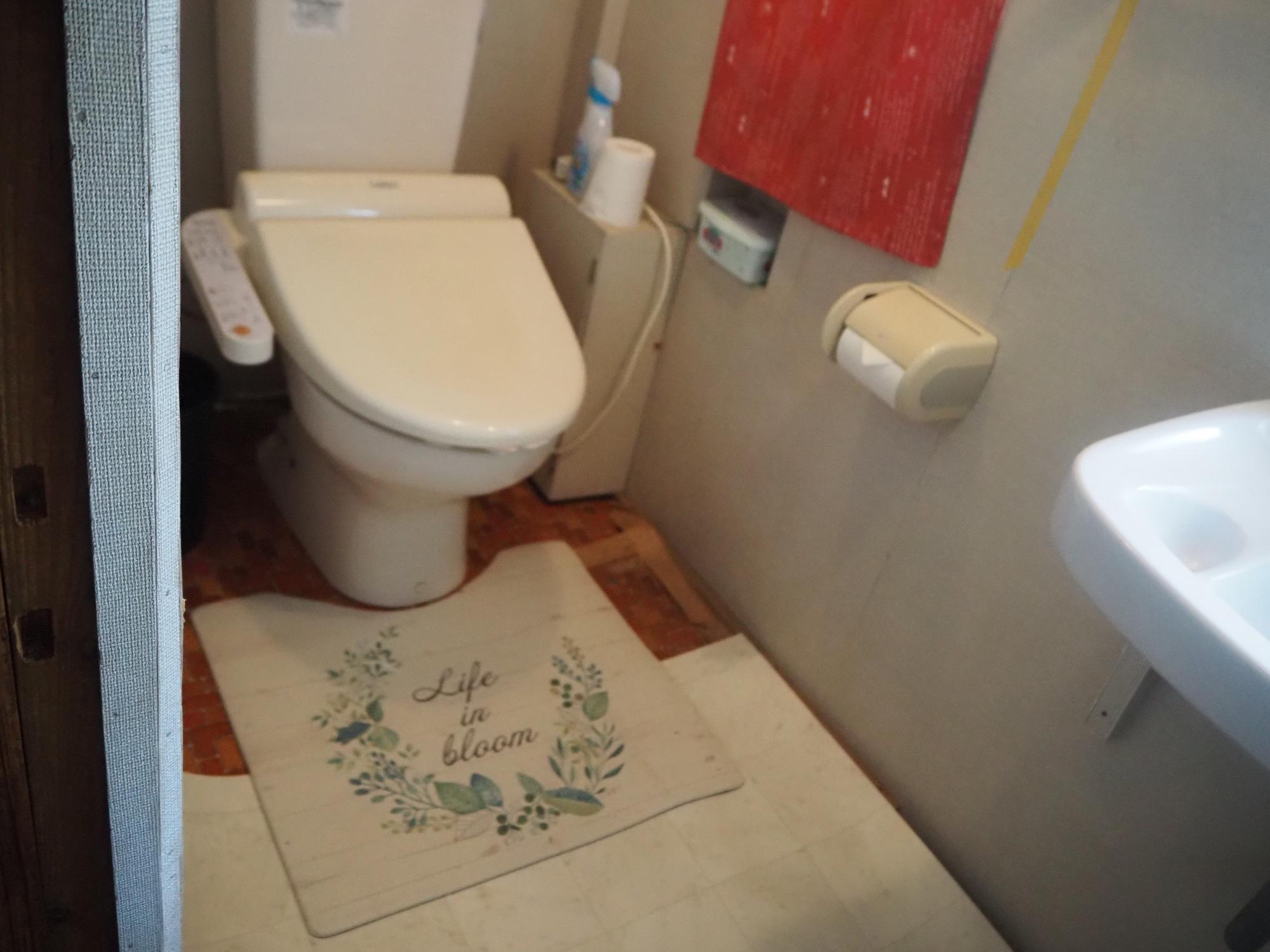 薄ピンクのウォシュレット付き便座と手洗い場も付いたトイレの写真