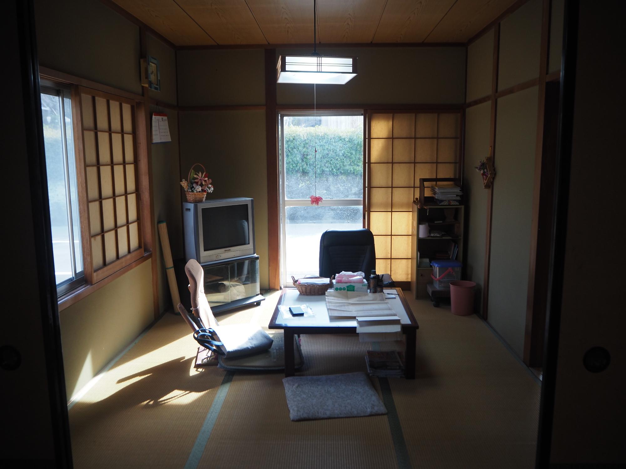 奥にテレビが有り、座椅子と机が真ん中に有る居間