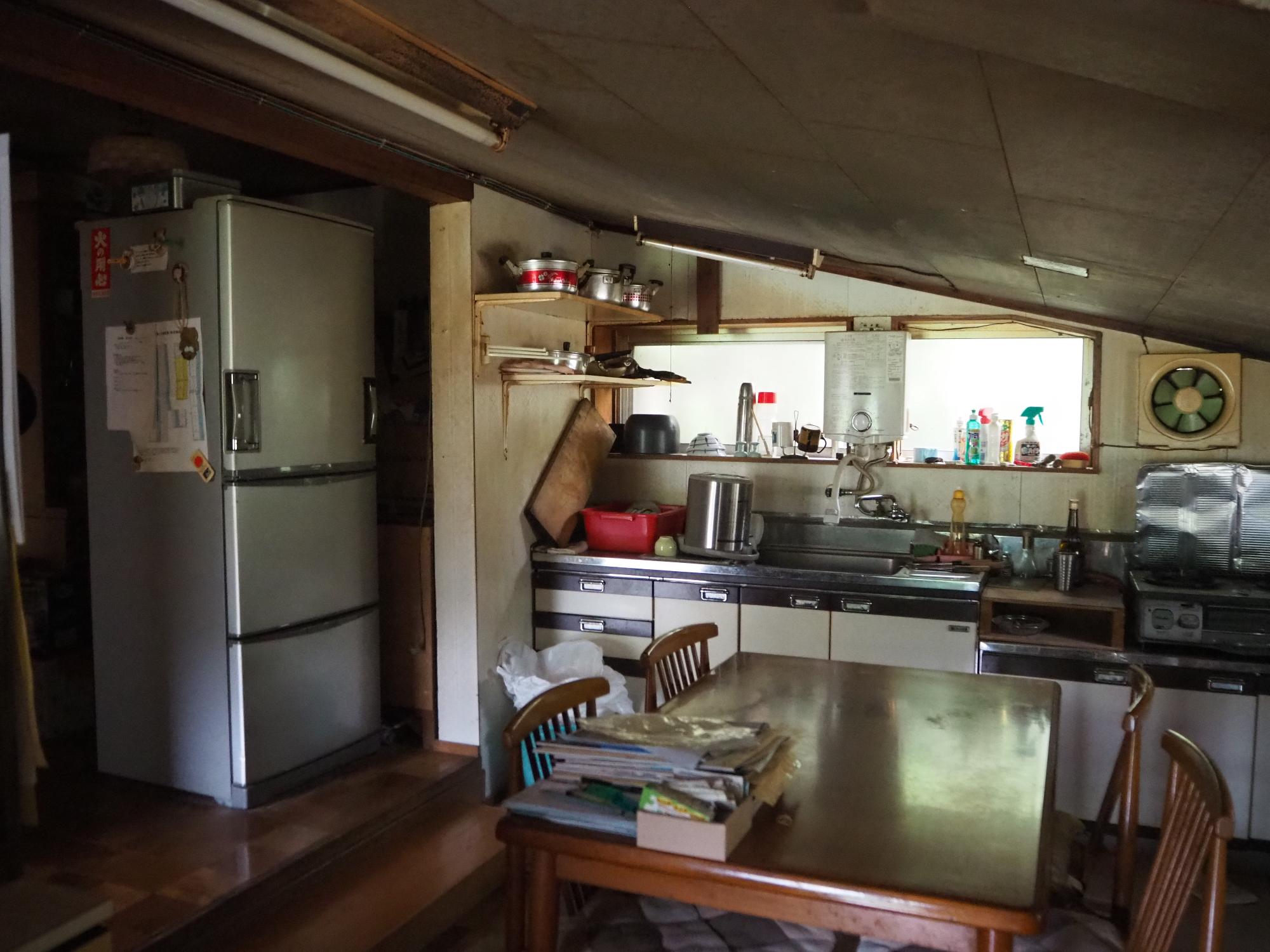斜めの屋根の下にキッチンや食卓が並ぶ台所の写真