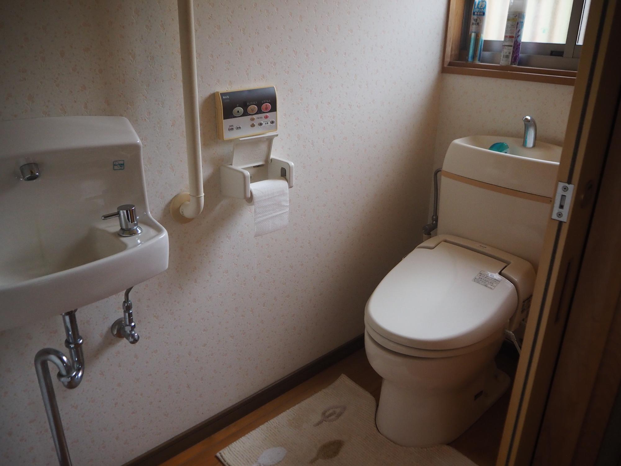 ウォシュレット付きで手洗い器が有るピンク色の様式トイレの写真