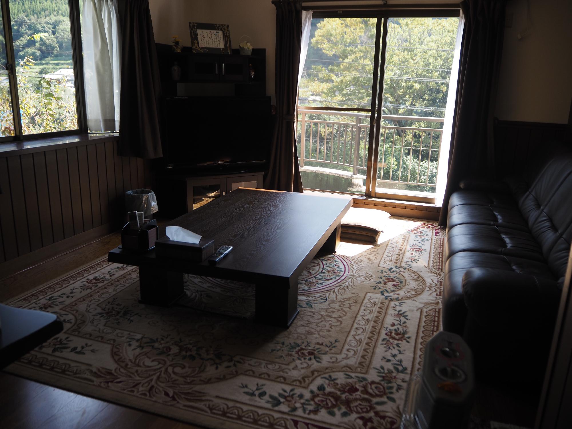 中央に机、壁側にソファがあるダークブラウンを基調としたリビング