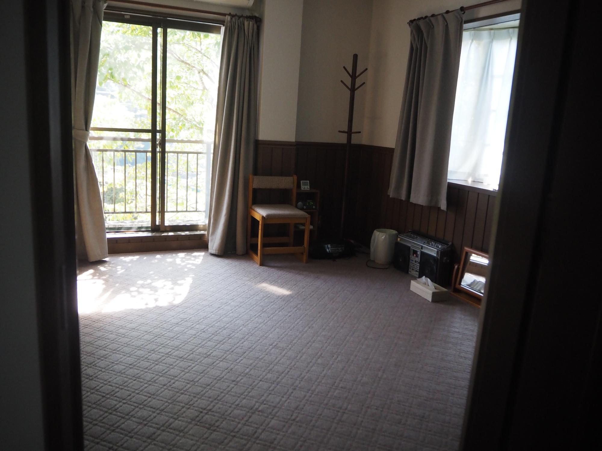 正面に窓、右側に出窓があるフローリングにライトグレーの絨毯が敷かれている洋間