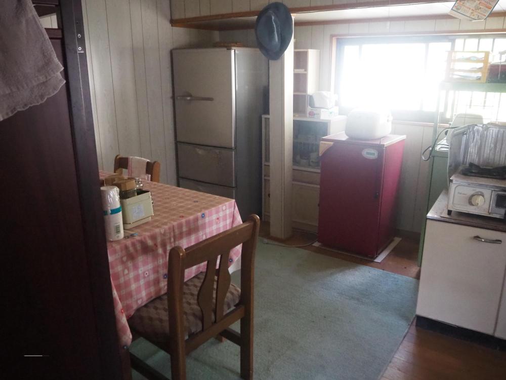 冷蔵庫や棚などが置かれたままの台所の写真