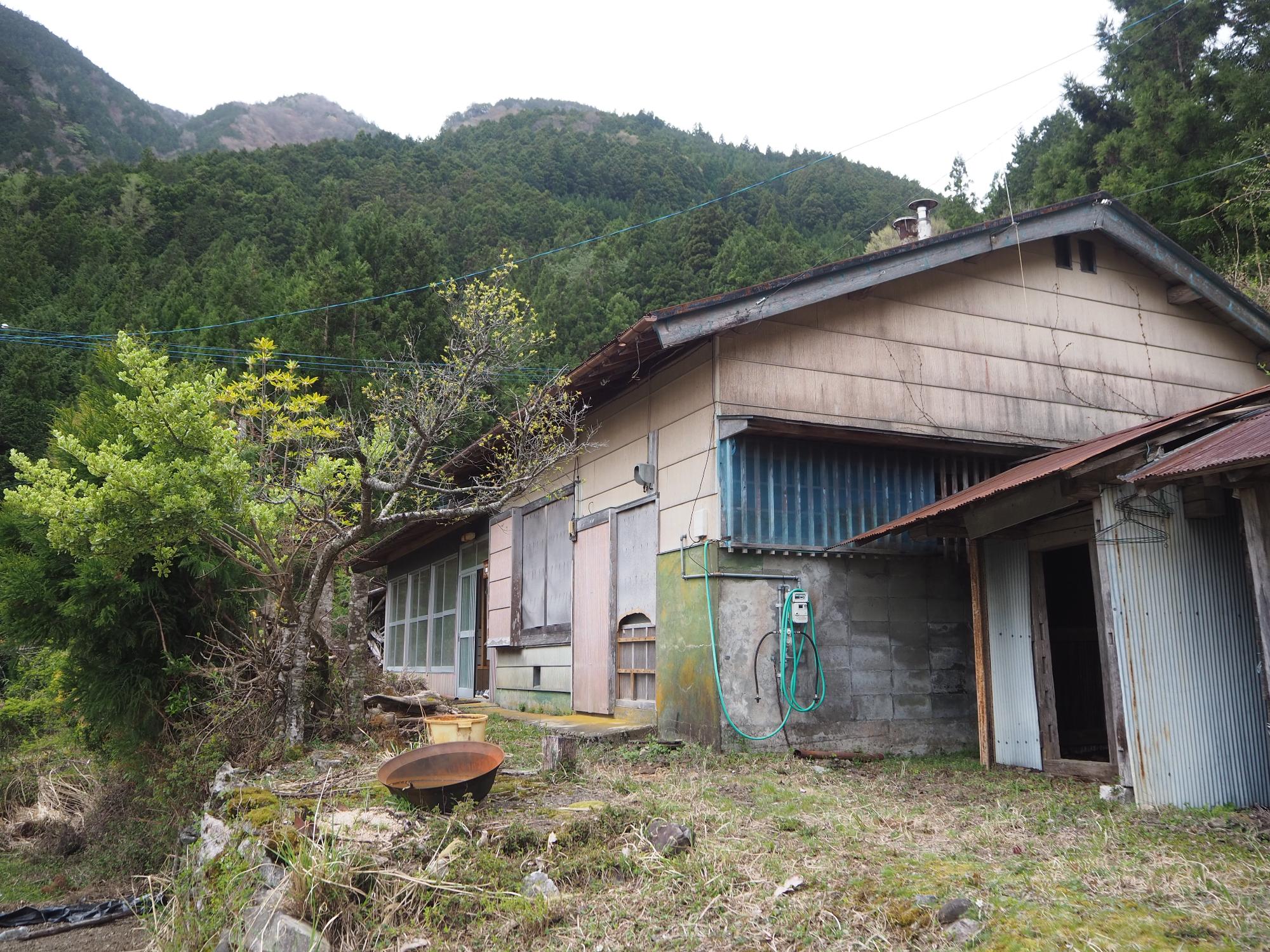 木々を背景に茶色の外壁で木造平屋の外観写真