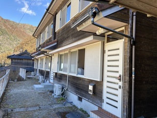 横に長い2階建ての建物で白い扉の玄関となっている木沢移住支援施設の外観写真