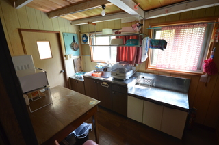 窓があり、流し台の上に換気扇が備え付けられているキッチンの写真