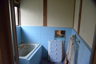 水色のタイルの壁に鏡が設置された浴室の写真