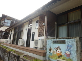 くま、うさぎ、きつねのイラストが描かれ「ひらの幼稚園」と書かれた門が立つ、平屋建ての平野シェアハウスの外観写真