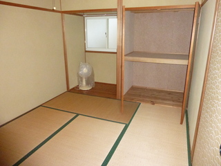 2段に分かれた押し入れとその横に窓、扇風機が置かれた和室の写真