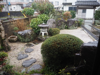 丸く剪定された植栽、飛び石や灯篭が設置された庭園の写真