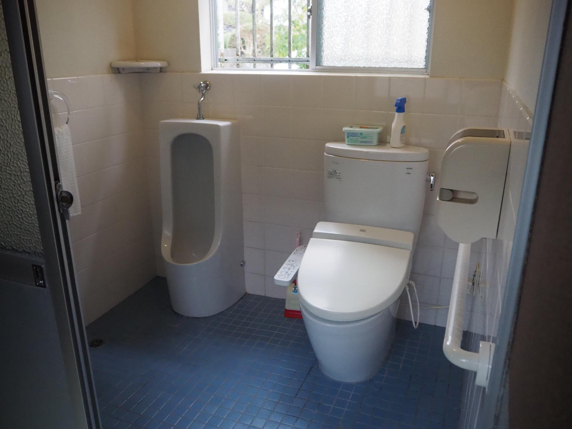 壁下半分と床がタイル張りで、横並びで小便器と洋式トイレが設置されているトイレの写真