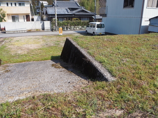 下へと向かうコンクリートのスロープの先にある更地になっている雑種地の写真