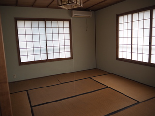 右上にエアコンが設置され、畳の敷かれた和室の写真