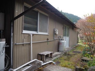 木々を背景に茶色の外壁で木造平屋の外観写真