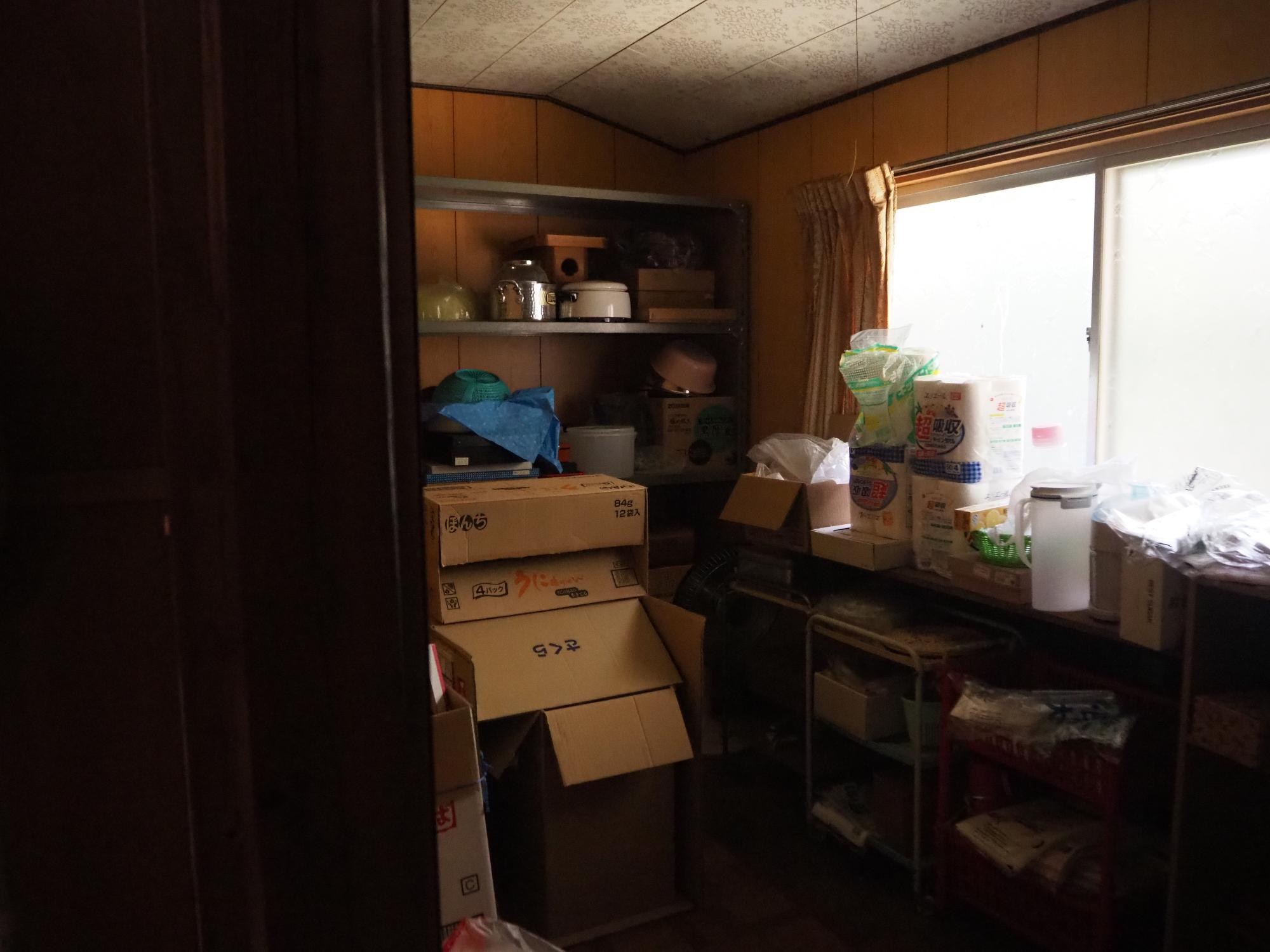 窓があり、段ボールや生活雑貨が沢山ある倉庫の写真