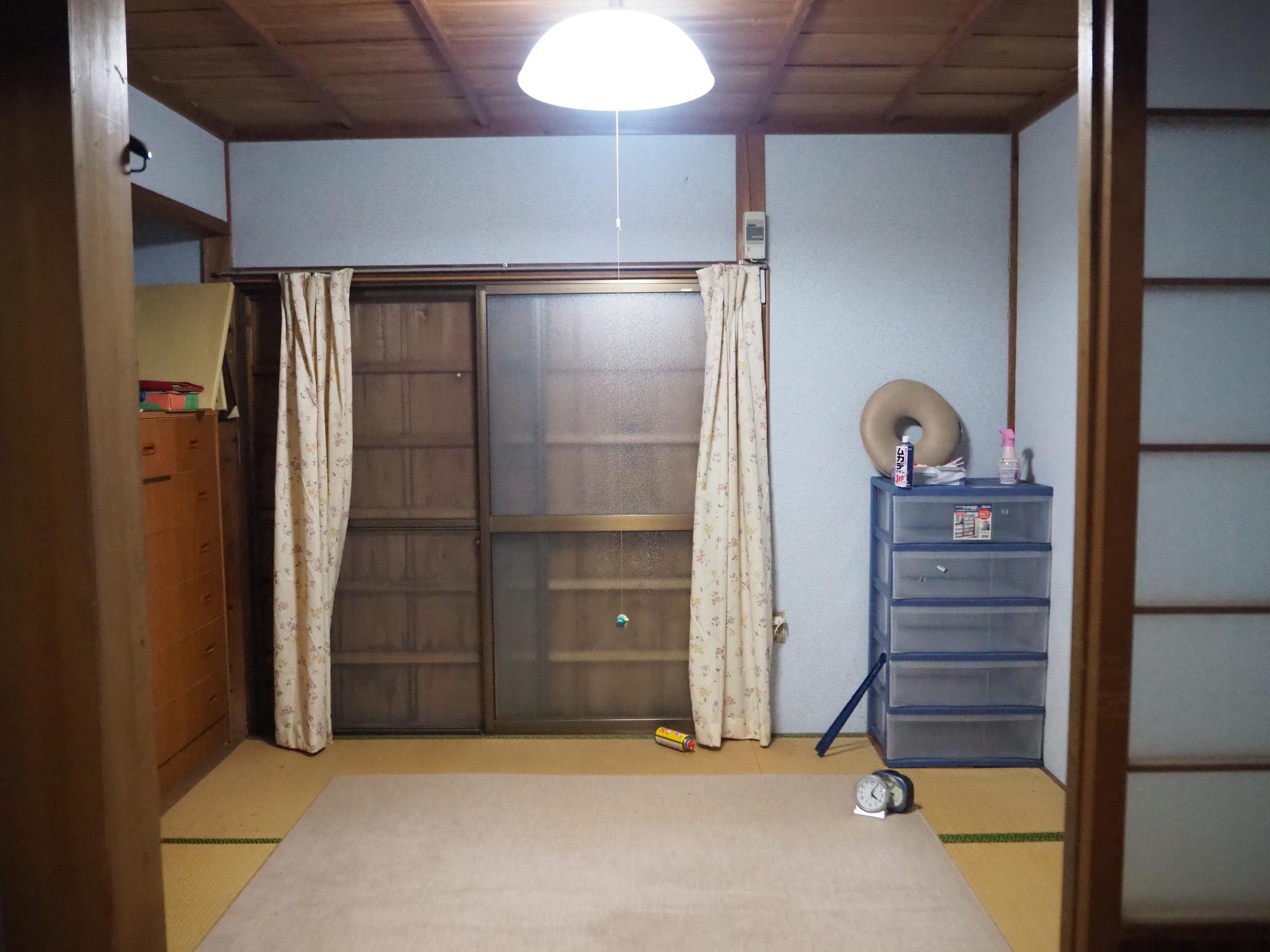窓に黄色の柄のカーテンが付けられ畳の上に絨毯が敷かれた和室の写真