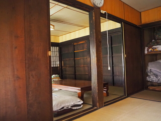 畳が敷かれ、時計やテーブルが置かれた室内の写真