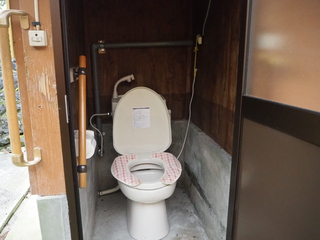 木目とコンクリートの壁に手すりが設置された洋式トイレの写真