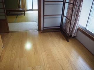 右側にピンクのカーテンが備え付けられた窓があり、フローリング床の部屋の写真