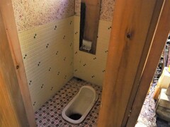 タイル張りの床と壁の和式トイレの写真