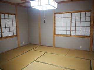 四角い和風の照明が設置され、向かって右側と左側の壁の窓に障子が設置されている和室の写真