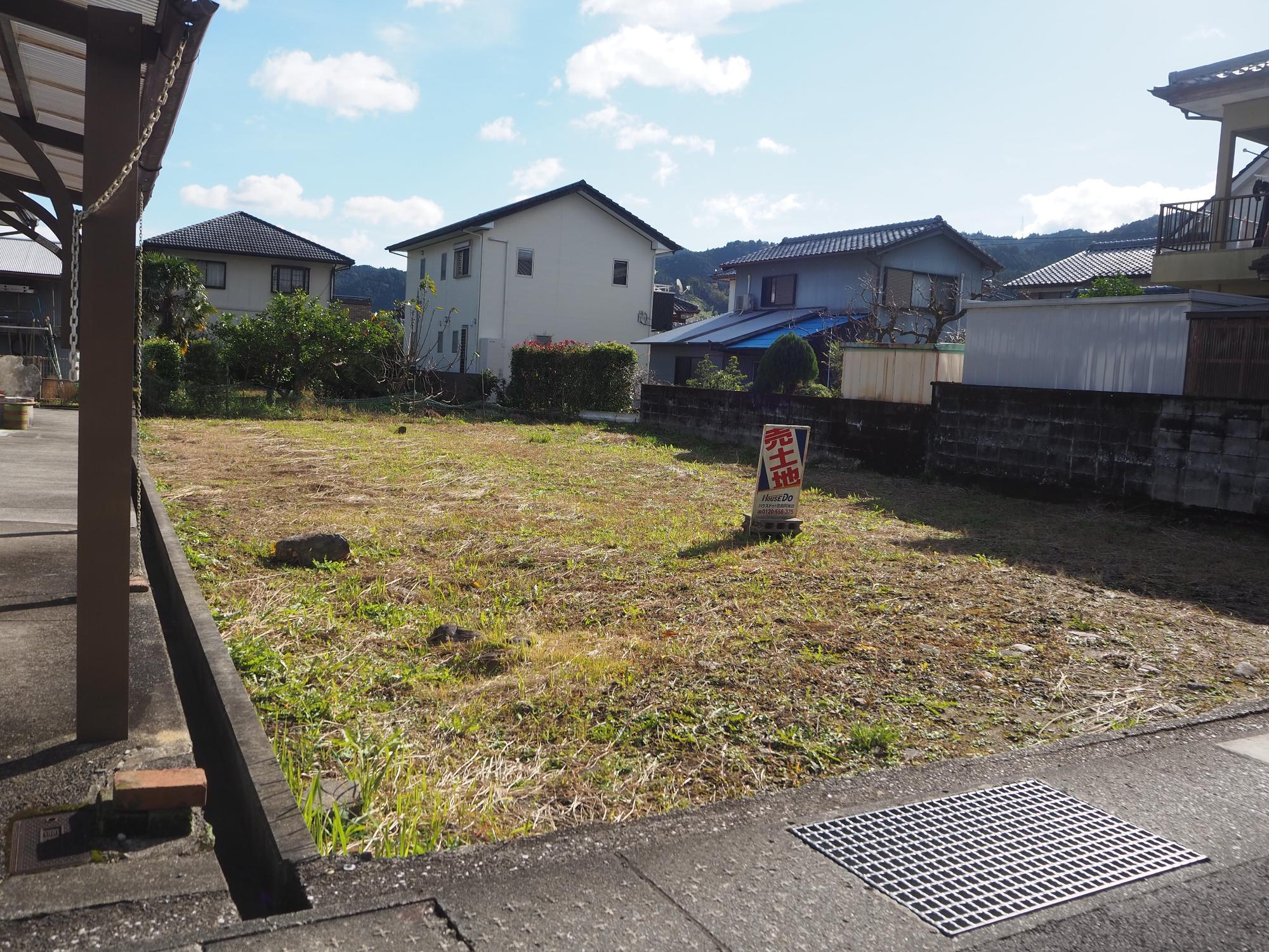 住宅に囲まれた場所にあり敷地の中央に「売土地」と書かれた看板が置かれた【売買】鷲敷 No.1-20の空地を写した写真