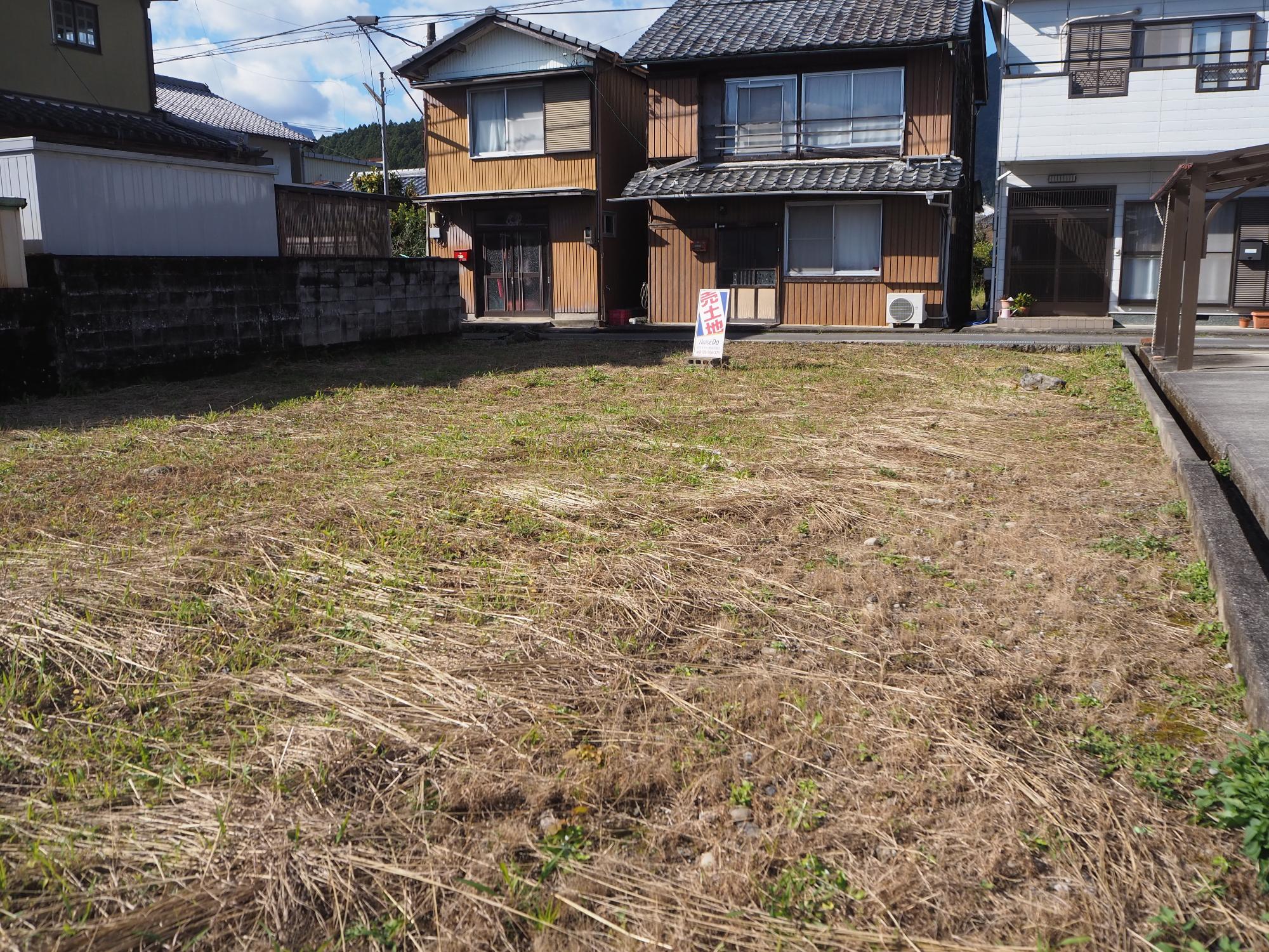 後ろに2階建ての家が並び、手前に広々とした空地のある写真