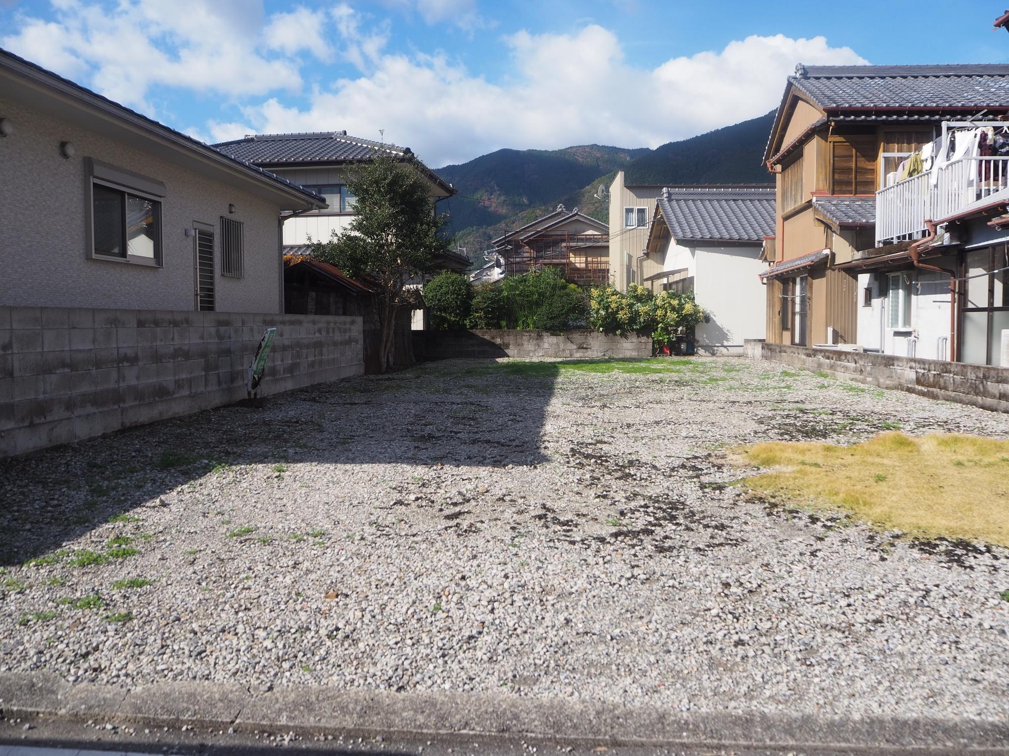 後方に山が見え、両脇には家が立ち並び、その間にある【売買】鷲敷 No.1-19の空き地の写真