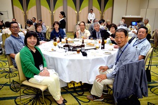白いテーブルクロスが引かれた丸テーブルについた人たちが、こちらを向いている写真