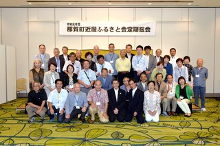 那賀町近畿ふるさと会定例総会と書かれた幕が張られたステージに並んでいる人たちの集合写真
