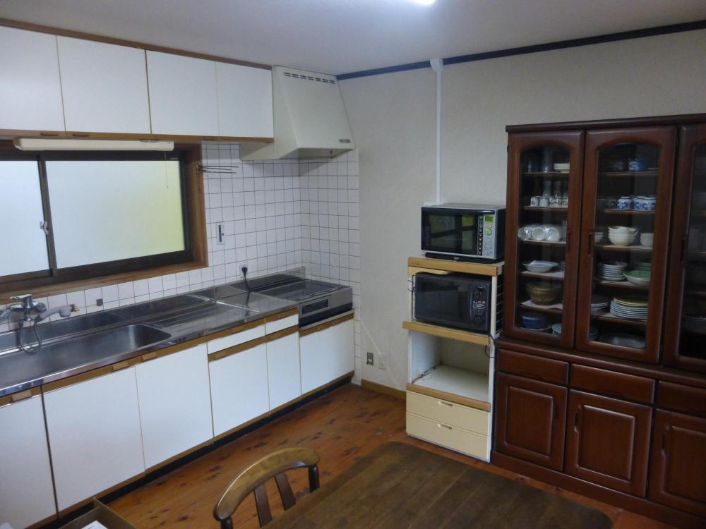 大きな食器棚とオール電化のキッチンの写真