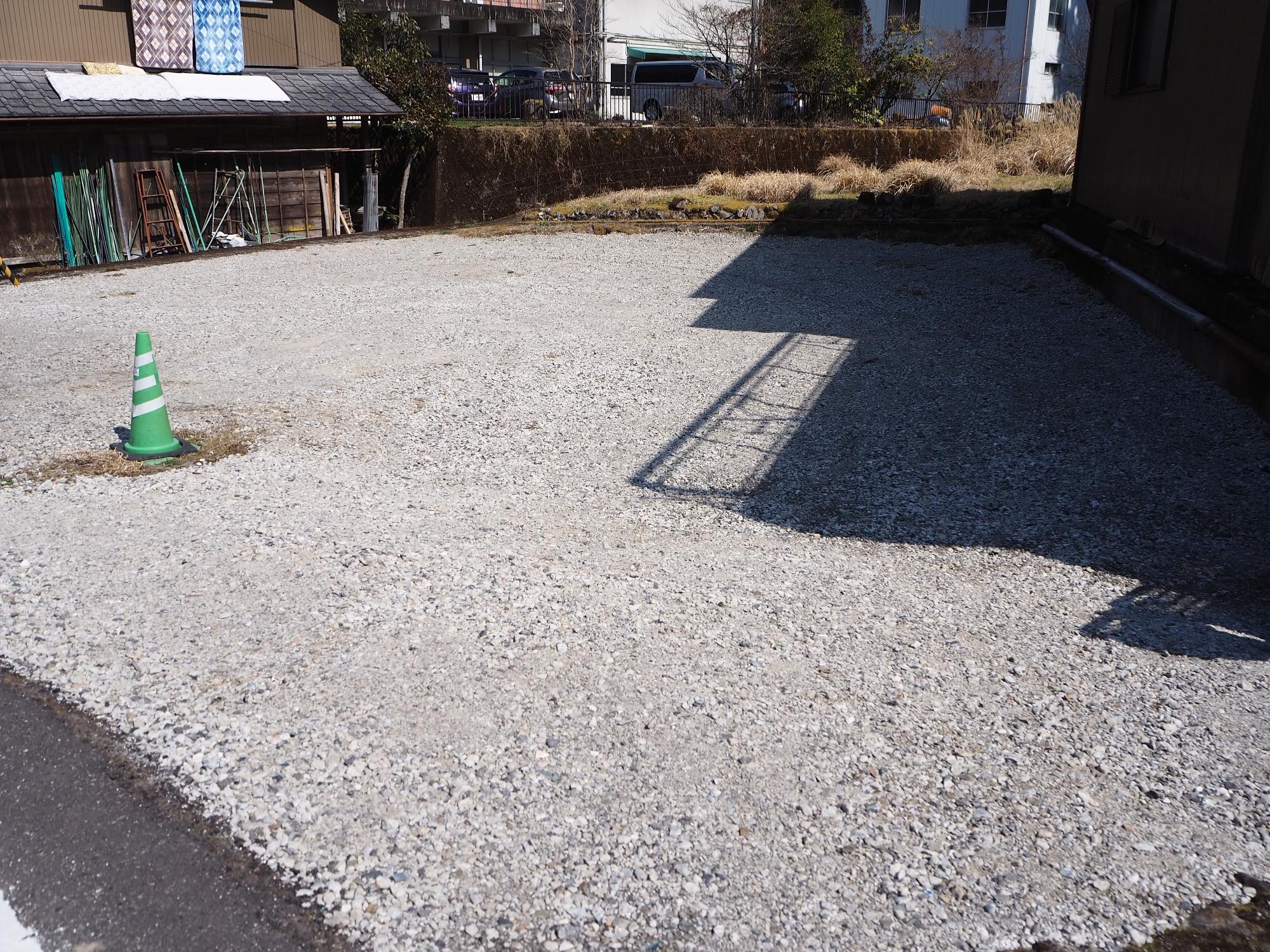 住宅に囲まれた場所にあり、左側に緑色の三角コーンが置かれ、砂利が敷かれた【売買・賃貸】上那賀 No.3-18の空き地の写真