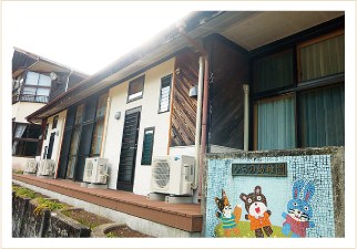 くま、うさぎ、きつねのイラストが描かれ「ひらの幼稚園」と書かれた門が立つ、平屋建ての平野シェアハウスの外観写真